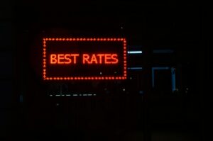 Glowing red neon sign displaying 'BEST RATES' against a dark background, illustrating the search for lowest mortgage rates and competitive credit score requirements